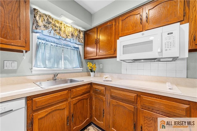 kitchen featuring white appliances, a sink, brown cabinetry, and light countertops