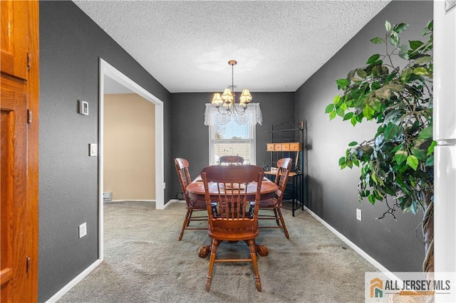 carpeted dining area featuring a chandelier, a textured ceiling, and baseboards