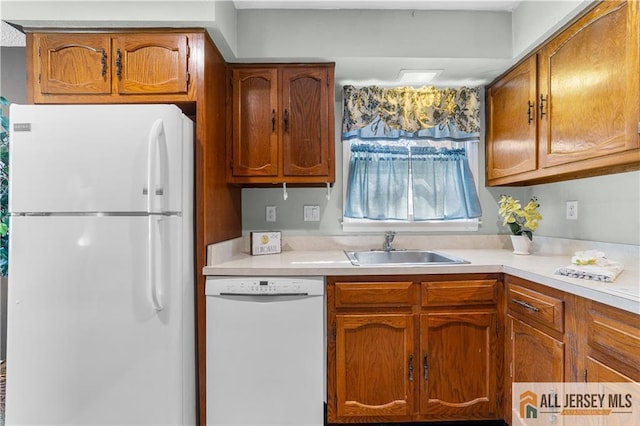 kitchen with white appliances, light countertops, brown cabinets, and a sink