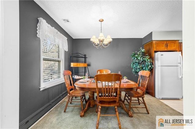 dining room with a chandelier, a textured ceiling, and light carpet
