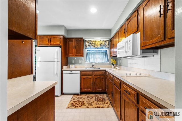 kitchen with white appliances, a sink, light floors, light countertops, and brown cabinetry