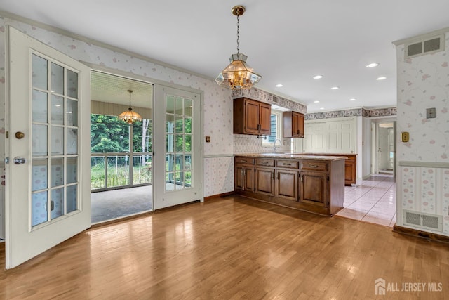 21 Shadyside Ct, Branchburg, NJ 08876 - kitchen featuring wallpapered walls, a peninsula, light wood finished floors, light countertops, and hanging light fixtures