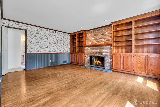 21 Shadyside Ct, Branchburg, NJ 08876 - unfurnished living room with wallpapered walls, light wood-type flooring, wainscoting, a brick fireplace, and ornamental molding