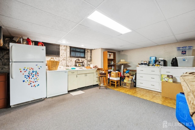 interior space featuring white refrigerator, a drop ceiling, and washer / clothes dryer