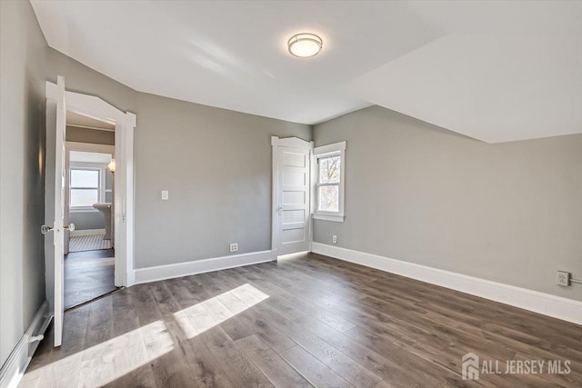 unfurnished bedroom featuring vaulted ceiling, dark wood-type flooring, and baseboards