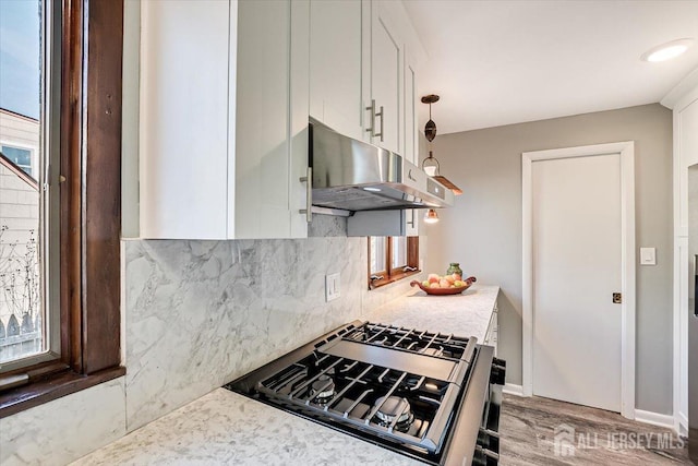 kitchen with decorative light fixtures, light countertops, under cabinet range hood, and white cabinetry