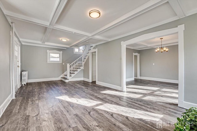 interior space featuring a notable chandelier, wood finished floors, baseboards, stairs, and radiator heating unit