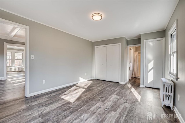 unfurnished bedroom with radiator, baseboards, and wood finished floors