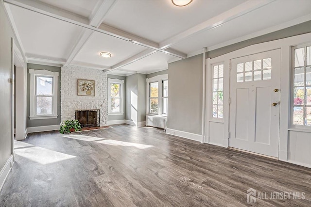 foyer featuring coffered ceiling, a fireplace, wood finished floors, radiator heating unit, and plenty of natural light