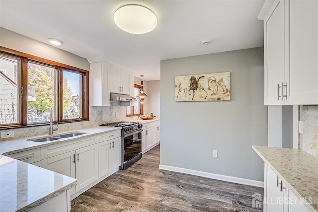 kitchen with range with gas cooktop, light stone counters, under cabinet range hood, white cabinetry, and a sink