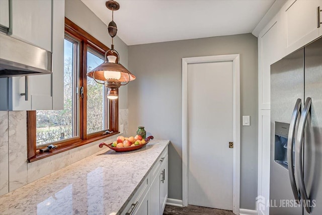 kitchen with white cabinets, light stone countertops, stainless steel refrigerator with ice dispenser, and decorative light fixtures