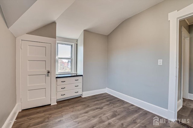 additional living space with baseboards, vaulted ceiling, and wood finished floors