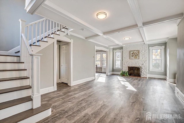 unfurnished living room featuring beam ceiling, a large fireplace, wood finished floors, baseboards, and stairs