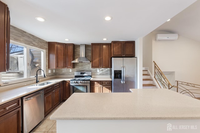 kitchen with tasteful backsplash, wall chimney range hood, a wall unit AC, stainless steel appliances, and a sink