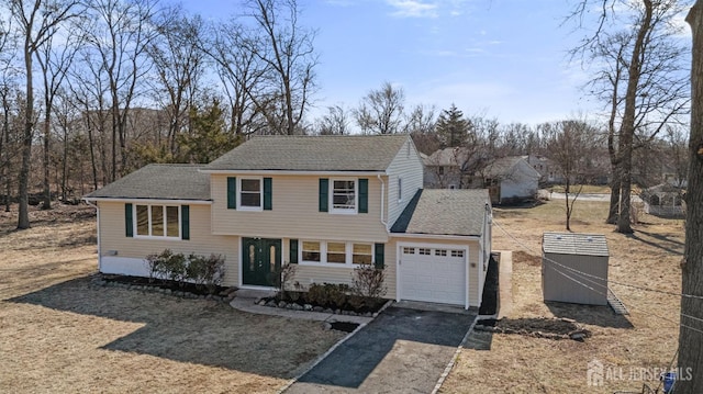 split level home featuring aphalt driveway, a garage, and a shingled roof