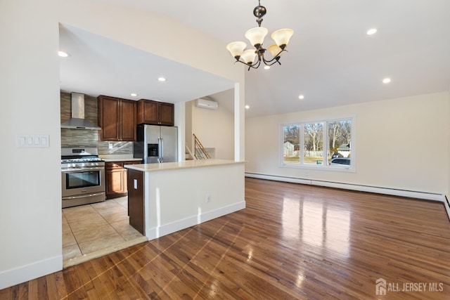 kitchen featuring tasteful backsplash, wall chimney range hood, an AC wall unit, light countertops, and stainless steel appliances