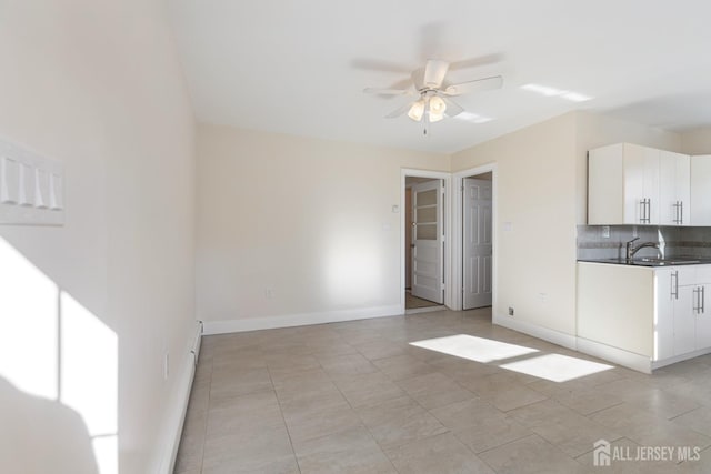 interior space with tasteful backsplash, white cabinets, baseboards, and ceiling fan