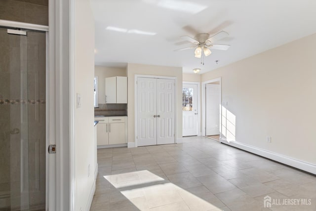 interior space featuring light tile patterned flooring, baseboards, and connected bathroom