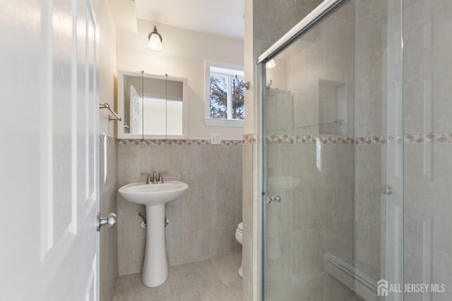 full bathroom with toilet, tile walls, a stall shower, and tile patterned flooring