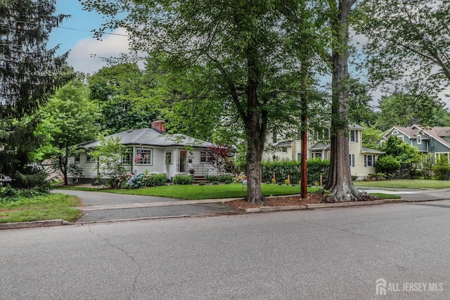23 Elm Ave, Metuchen, NJ 08840 - view of front facade featuring a chimney, a front lawn, and driveway