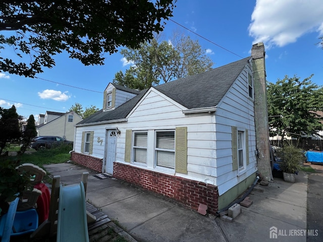 37 N Randolphville Rd, Piscataway, NJ 08854 - view of front of home with roof with shingles, a chimney, brick siding, and a patio area