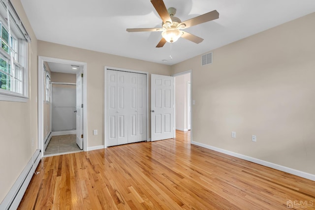 unfurnished bedroom featuring light wood finished floors, visible vents, baseboards, a baseboard radiator, and ensuite bathroom