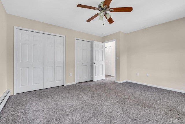 unfurnished bedroom featuring a baseboard heating unit, baseboards, carpet flooring, and multiple closets