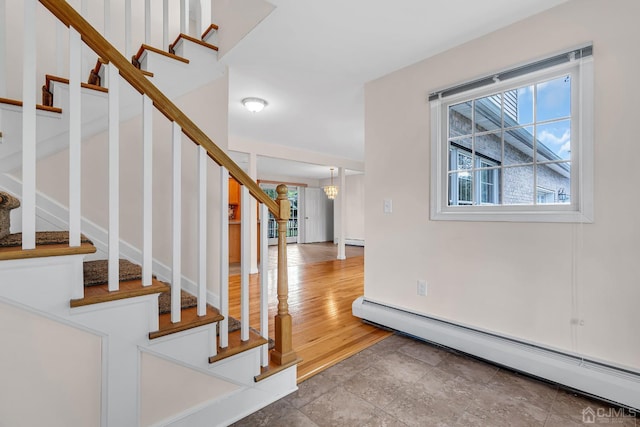 stairs featuring a baseboard heating unit and wood finished floors