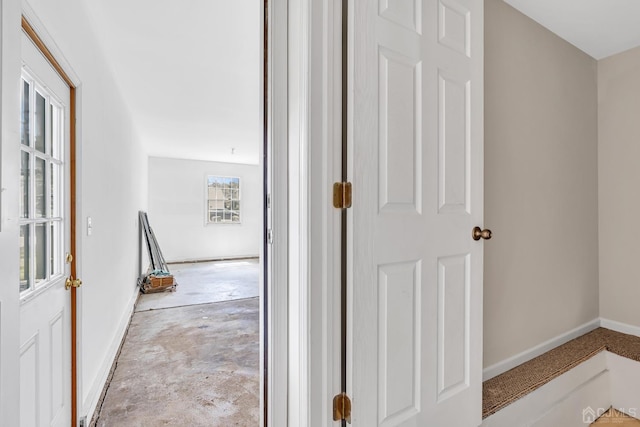 hallway with concrete floors and baseboards