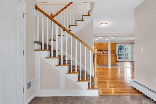 entrance foyer featuring light wood-style flooring, stairway, a baseboard radiator, and visible vents