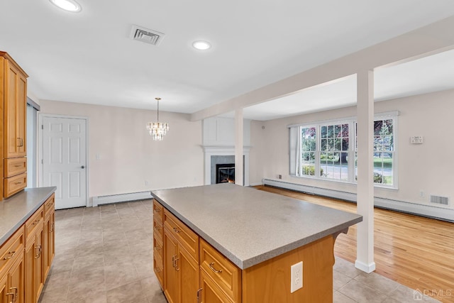 kitchen featuring a warm lit fireplace, visible vents, a baseboard radiator, a kitchen island, and recessed lighting