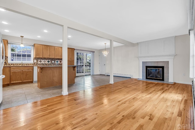 unfurnished living room featuring a sink, light wood finished floors, plenty of natural light, and a tiled fireplace