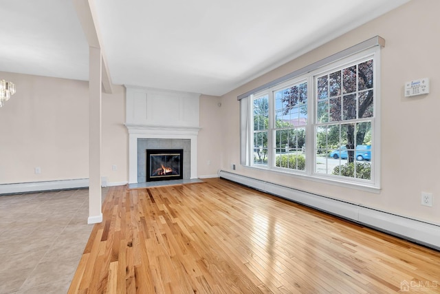 unfurnished living room featuring light wood-style floors, a baseboard radiator, a notable chandelier, and a tile fireplace