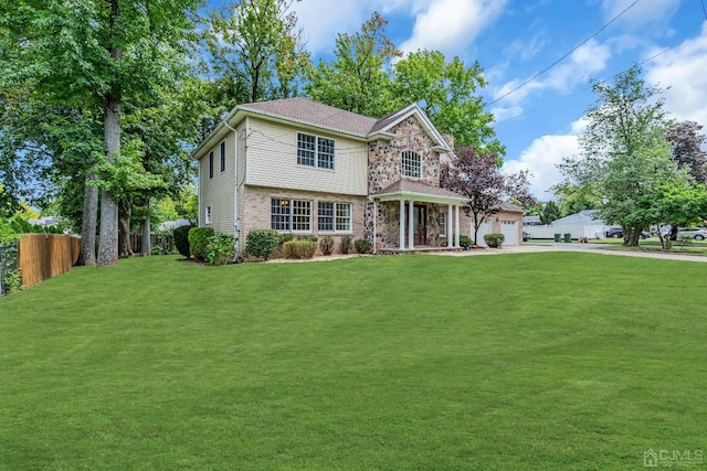 view of front of house featuring a front yard, stone siding, fence, and driveway