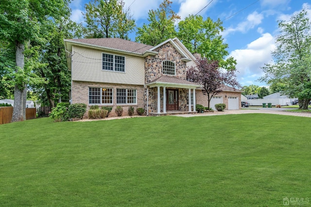 view of front facade with driveway, a garage, stone siding, fence, and a front yard