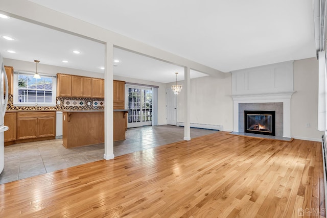 unfurnished living room featuring light wood-type flooring, a sink, a wealth of natural light, and a tile fireplace