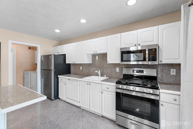 12 Arbor Ct, South Brunswick, NJ 08852 - kitchen with appliances with stainless steel finishes, washer and clothes dryer, white cabinets, tasteful backsplash, and tile countertops