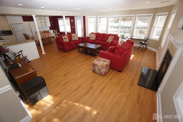 living area featuring recessed lighting, a healthy amount of sunlight, a fireplace, and light wood finished floors