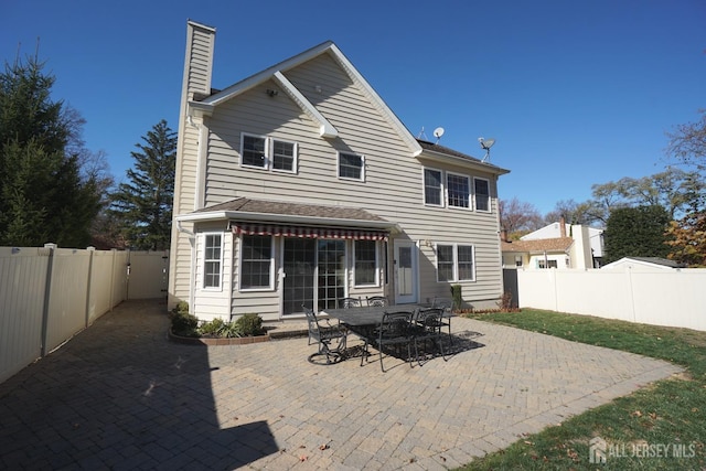 rear view of house with a patio, a fenced backyard, and a chimney