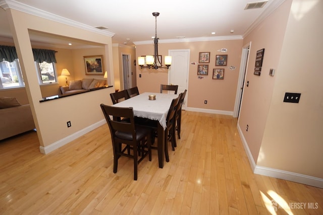 dining room with visible vents, baseboards, ornamental molding, an inviting chandelier, and light wood-style floors