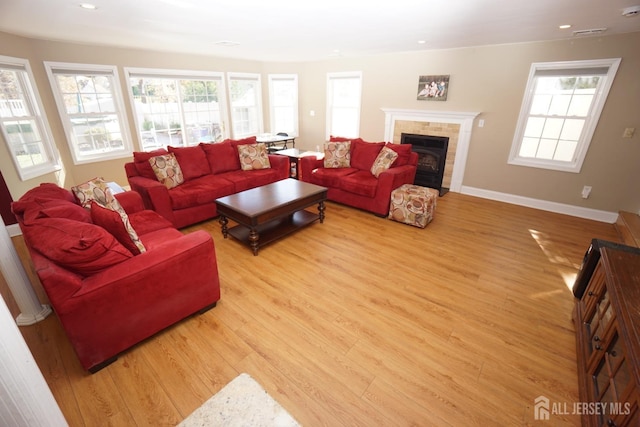 living area featuring a fireplace, recessed lighting, baseboards, and light wood-type flooring