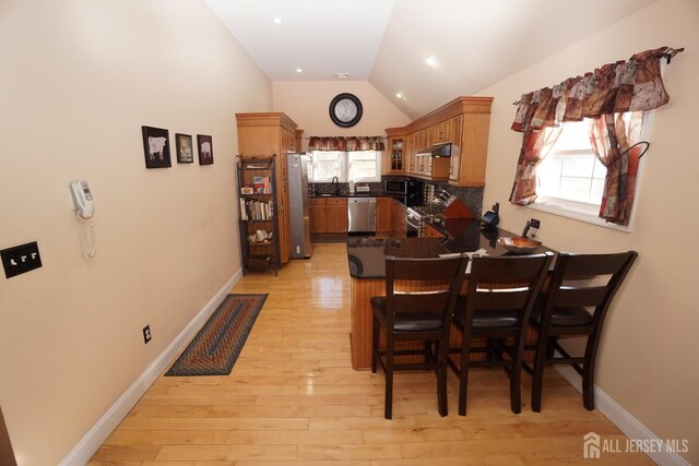 dining room with lofted ceiling, recessed lighting, baseboards, and light wood finished floors