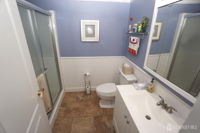 bathroom featuring vanity, toilet, baseboards, and a shower with shower door