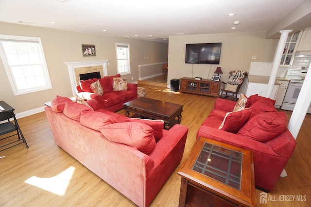 living room featuring recessed lighting, light wood-type flooring, a fireplace, and ornate columns