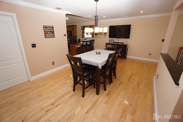 dining room with an inviting chandelier, crown molding, light wood-style floors, and baseboards