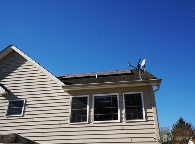 view of side of property with roof mounted solar panels