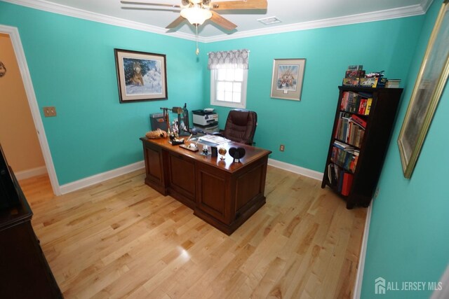 office space with light wood-type flooring, visible vents, crown molding, baseboards, and ceiling fan