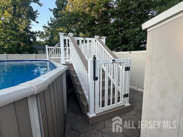 view of swimming pool featuring a fenced in pool, a wooden deck, stairs, and fence