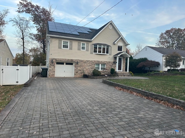 view of front facade featuring a garage, a front lawn, and solar panels