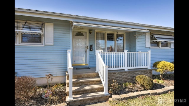 view of exterior entry featuring covered porch